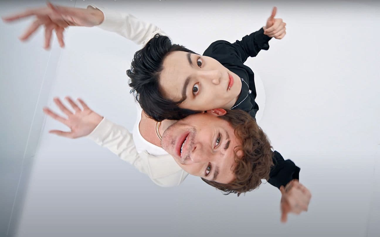 Charlie Puth e Jungkook sorriem para a câmera em um cenário branco