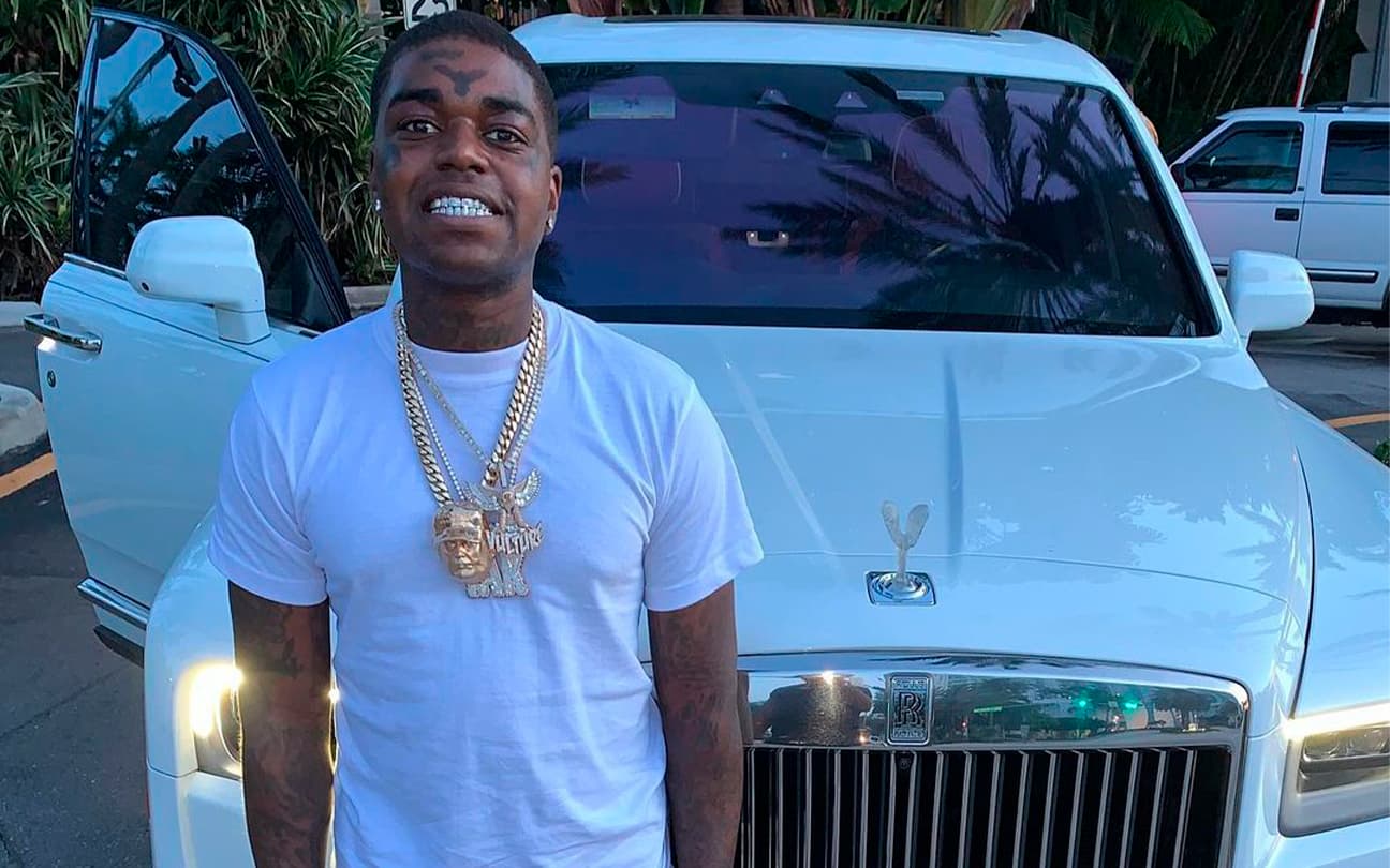 Kodak Black sorri para foto em frente a carro de luxo