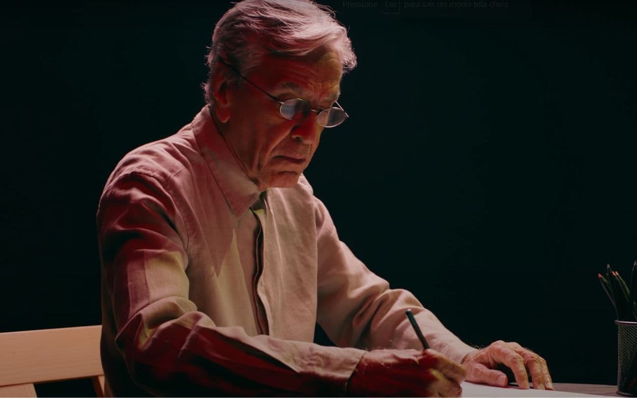 Caetano Veloso escrevendo, sentado em estúdio