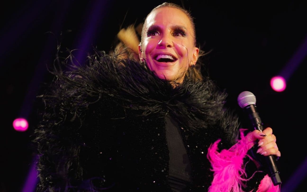 Ivete Sangalo usa vestido de plumas e segura microfone durante show