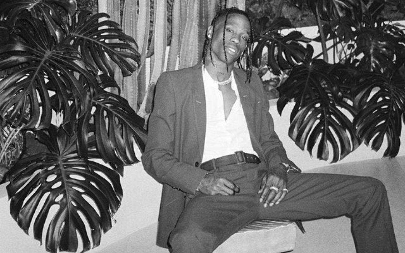 Travis Scott sentado em sofá, rodeado por plantas