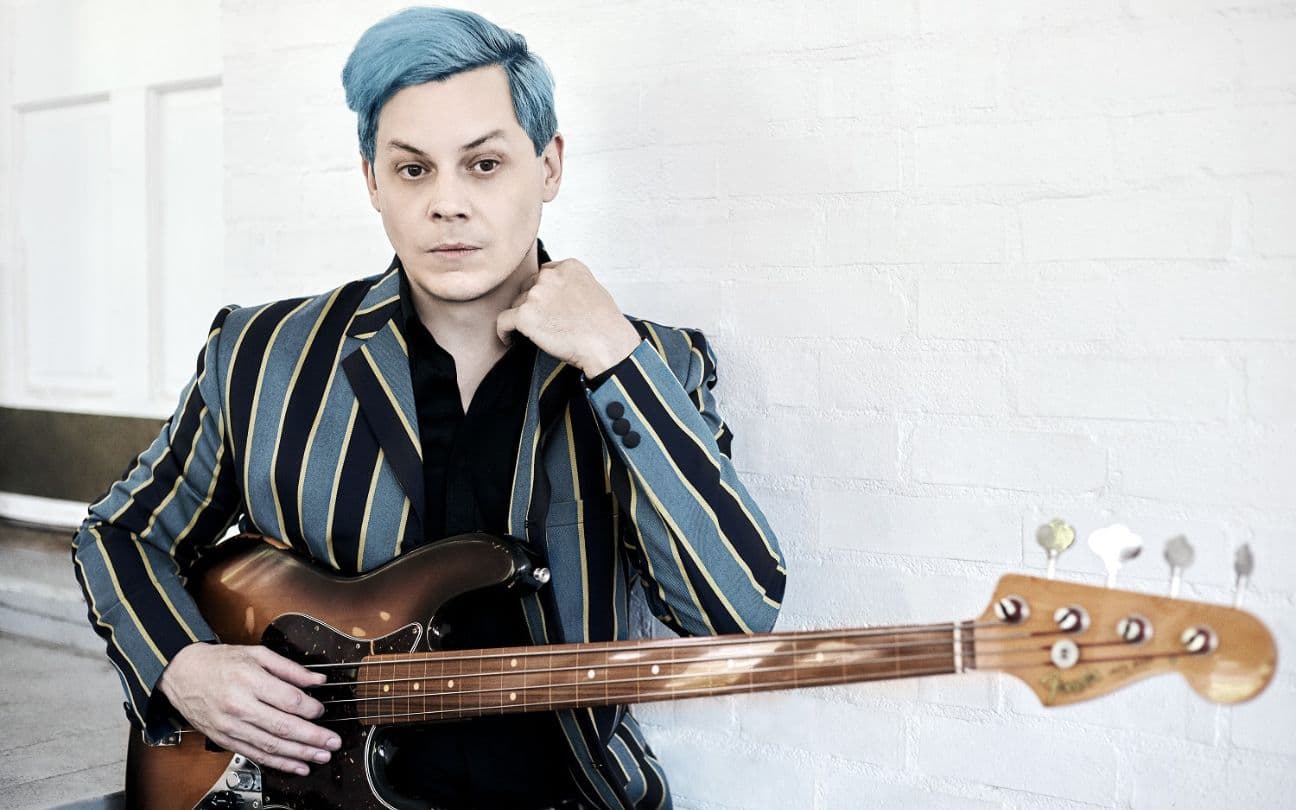 Jack White sentado com guitarra na mão