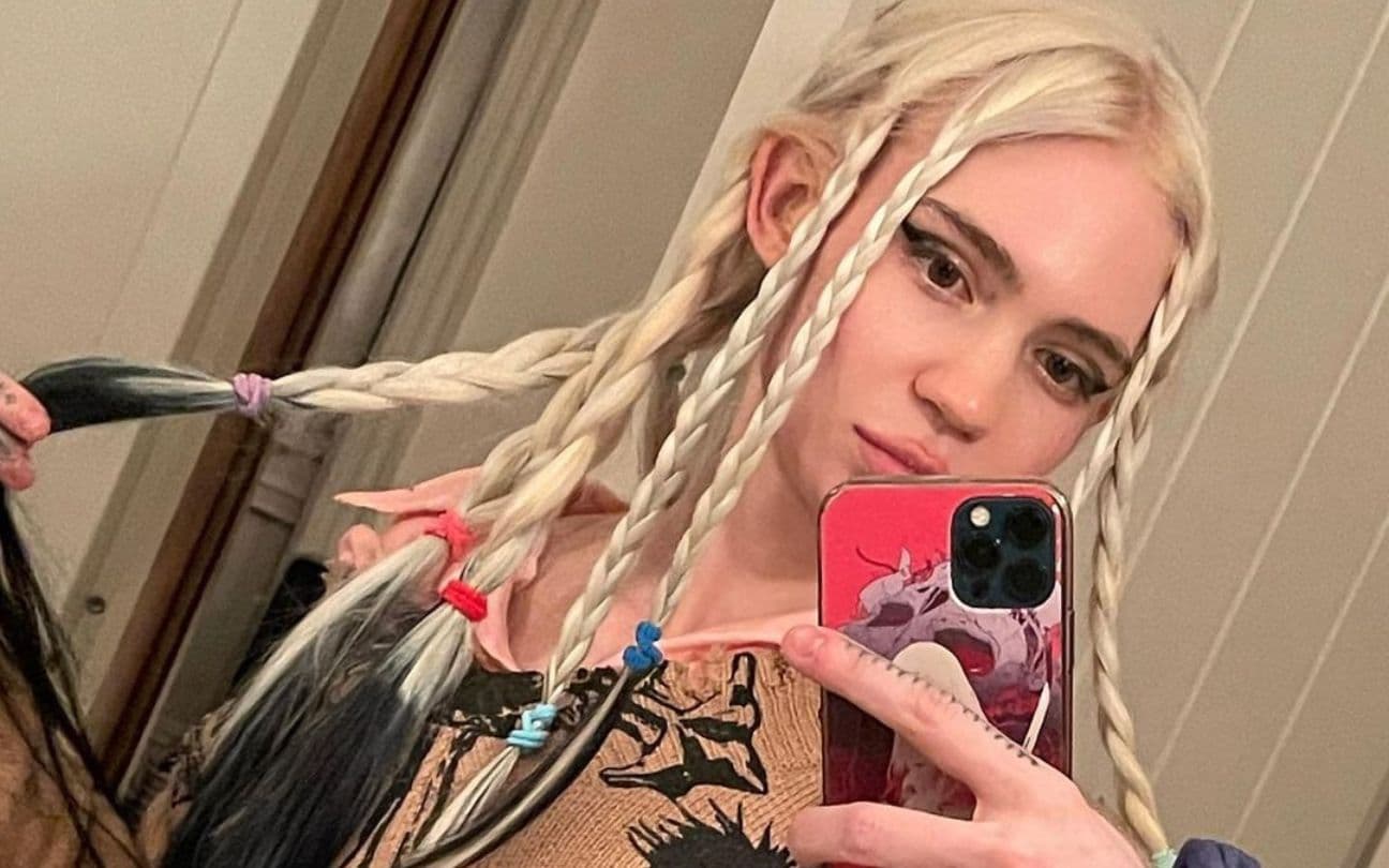 Grimes posa para foto em frente a espelho