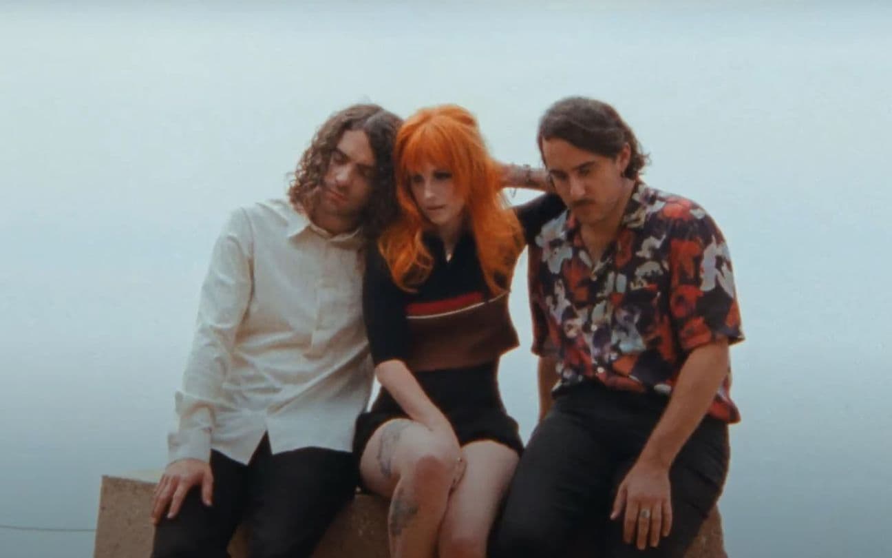 Membros do Paramore abraçados em um banco