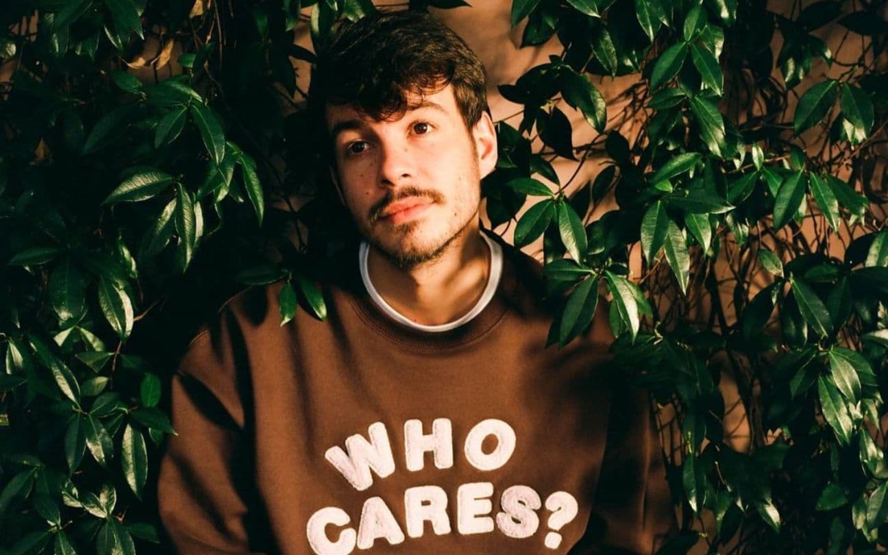 O cantor Rex Orange County sentado ao redor de plantas