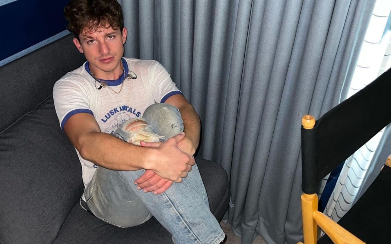 Charlie Puth sentado em um sofá