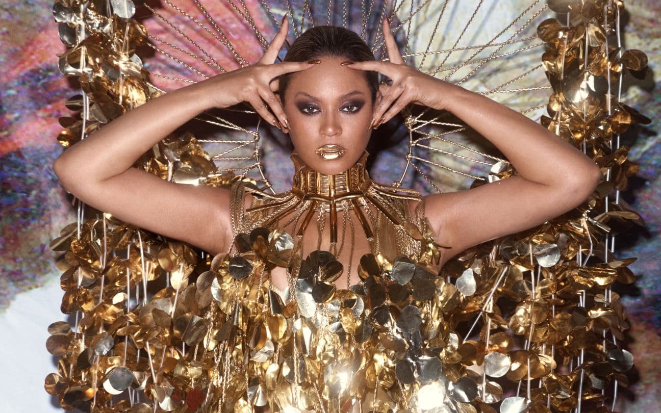 Beyoncé com as mãos na cabeça e um vestido dourado