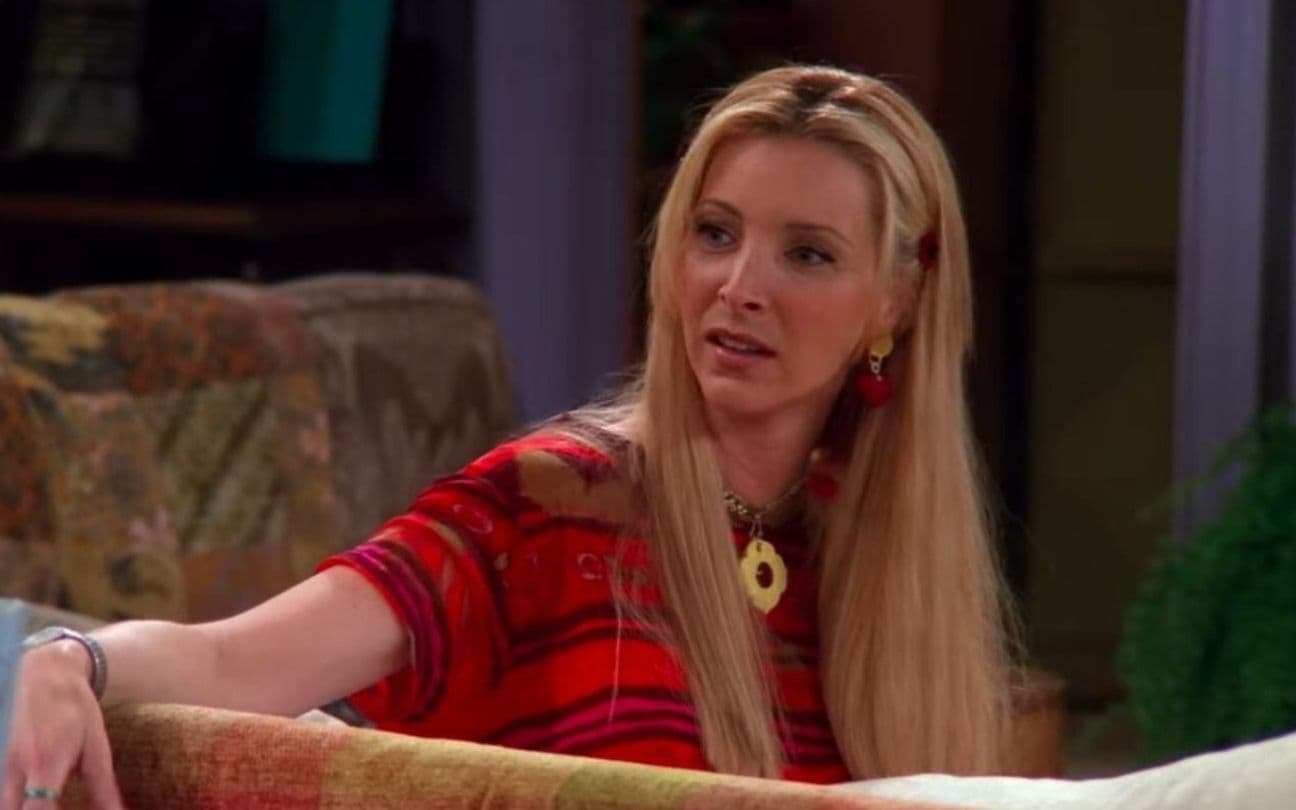 Lisa Kudrow sentada em sofá em cena de Friends