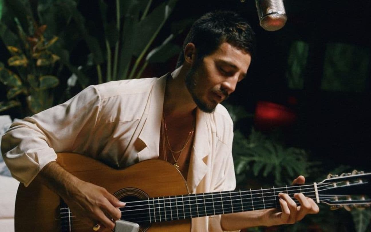 Tiago Iorc toca violão sentado