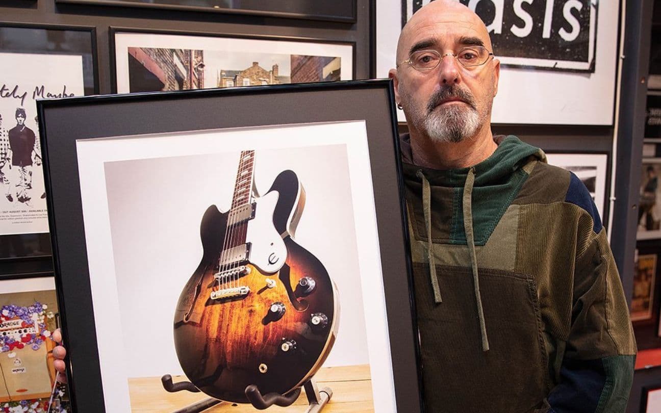 Paul Arthurs, do Oasis, ao lado de uma fotografia de uma guitarra