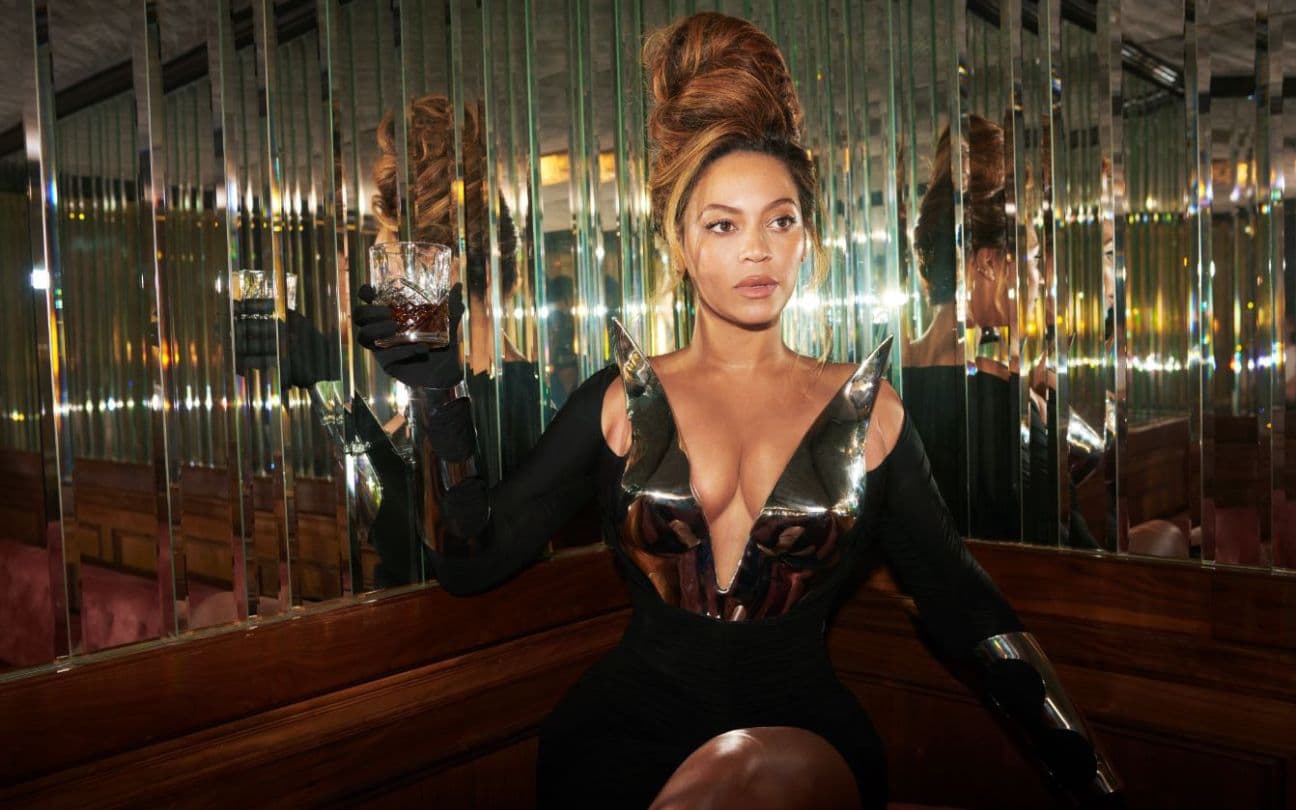 Beyoncé segura um drink ao lado de uma parede espelhada