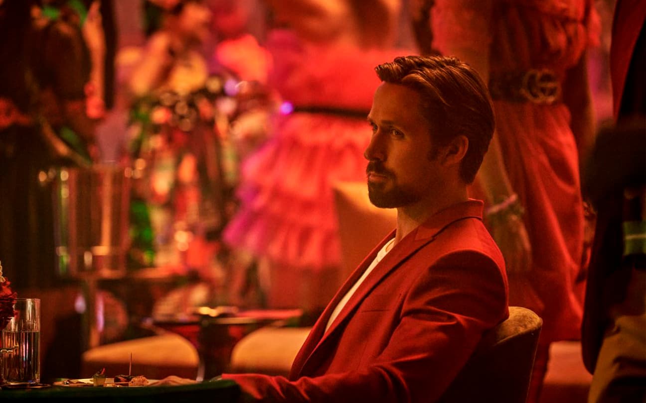Ryan Gosling sentado em cadeira, no filme Agente Oculto (2022)