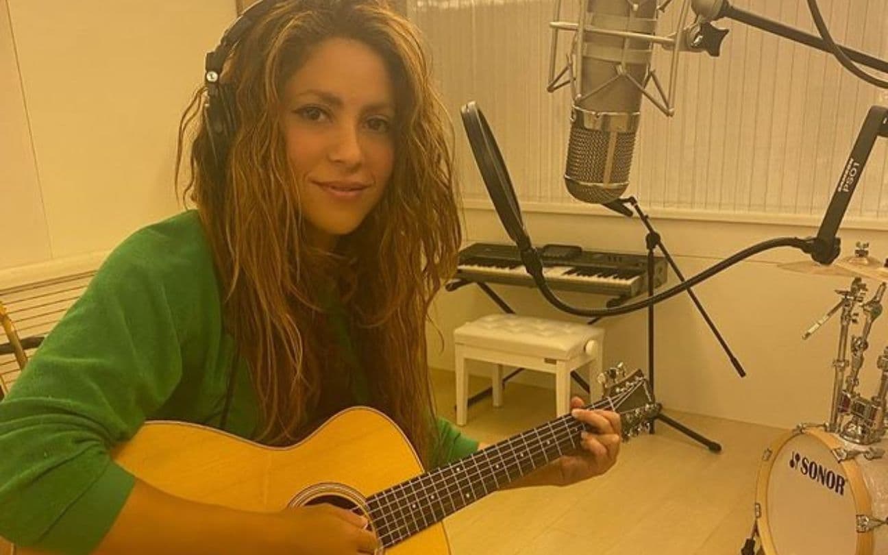 Shakira sentada com violão em um estúdio